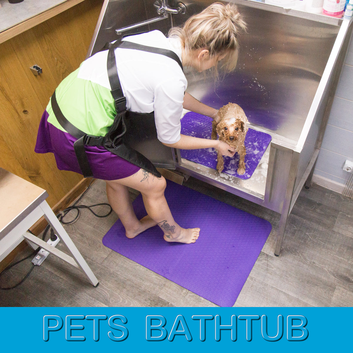 Purple non-slip grooming mats used in a pet bathtub and under a groomer’s feet for safer, more comfortable grooming
