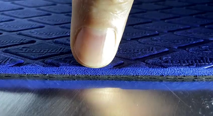 Blue SEGULMAT Multipurpose EVA dog grooming table mat showing soft cushioning and layered construction under finger pressure