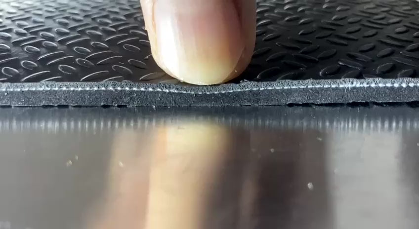 Black SEGULMAT Professional PVC dog grooming table mat showing firm cushioning and layered construction under finger pressure